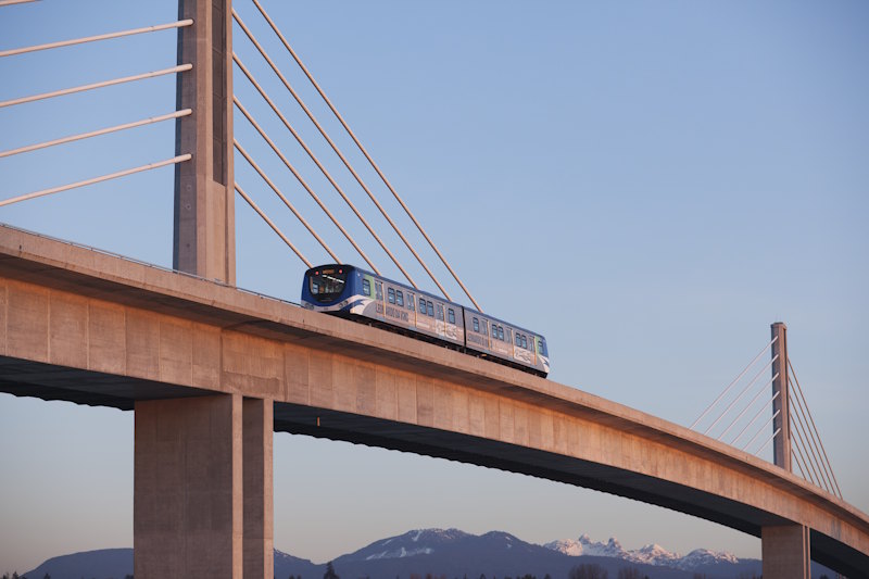 The Canada Line SkyTrain crossing a bridge with views of the North Shore Mountains in Vancouver